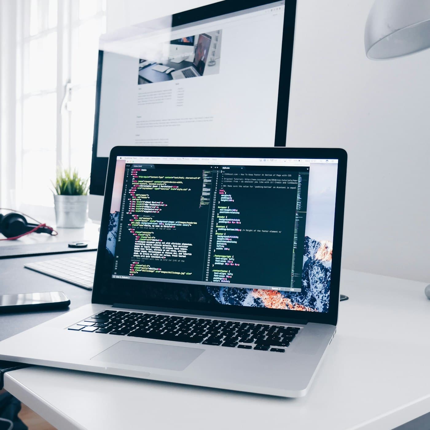 Laptop and monitor with code on a clean workspace